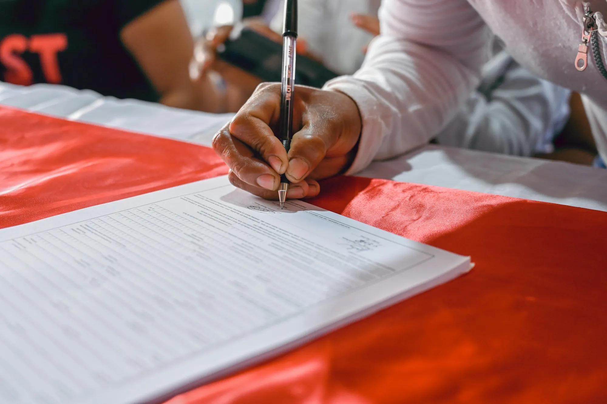 Person signing a stack of forms with a pen