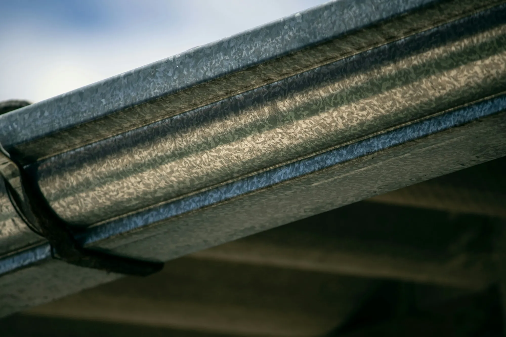 Close-up of a metal gutter and bracket under a roof edge