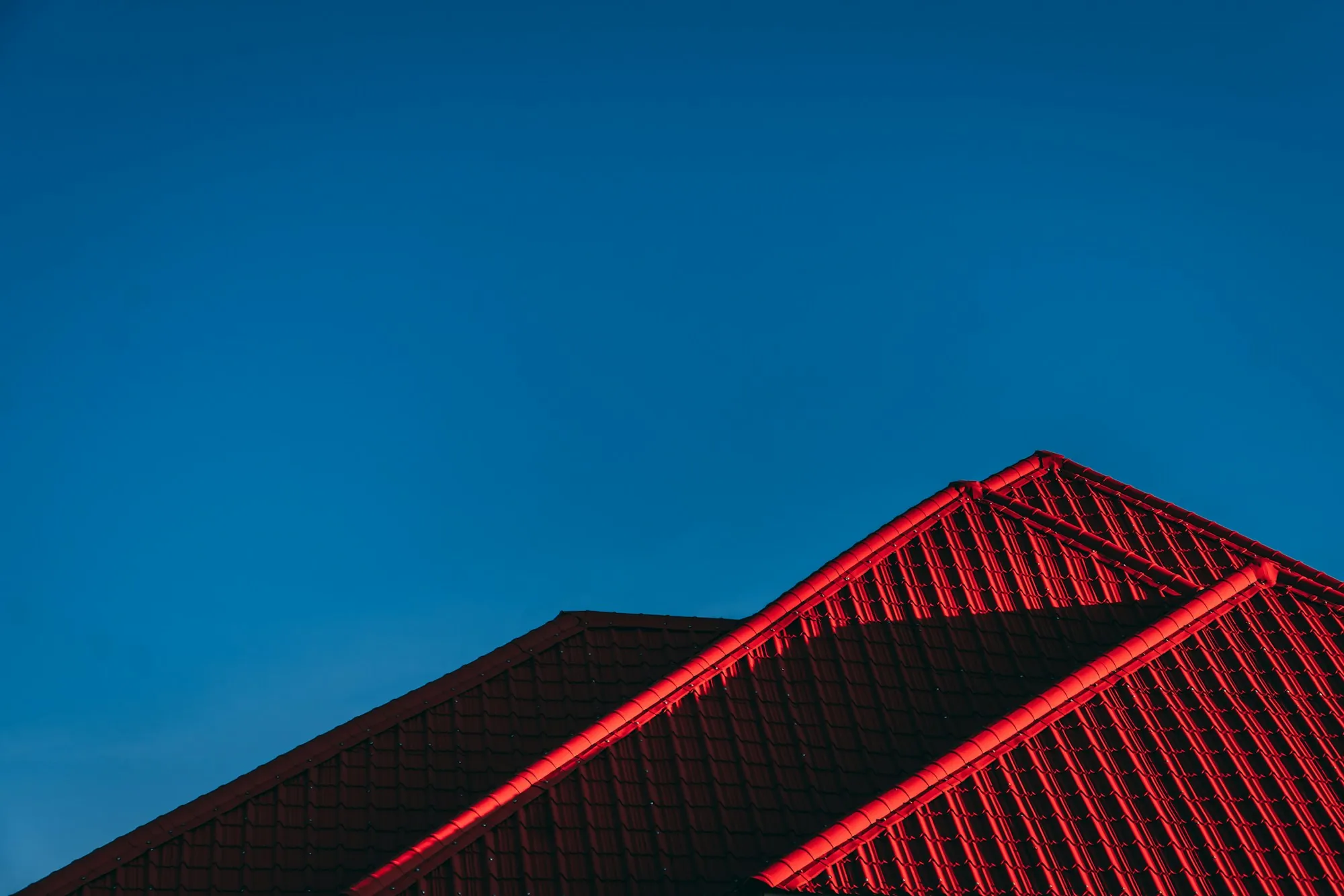 Bright red metal roof panels against a deep blue sky