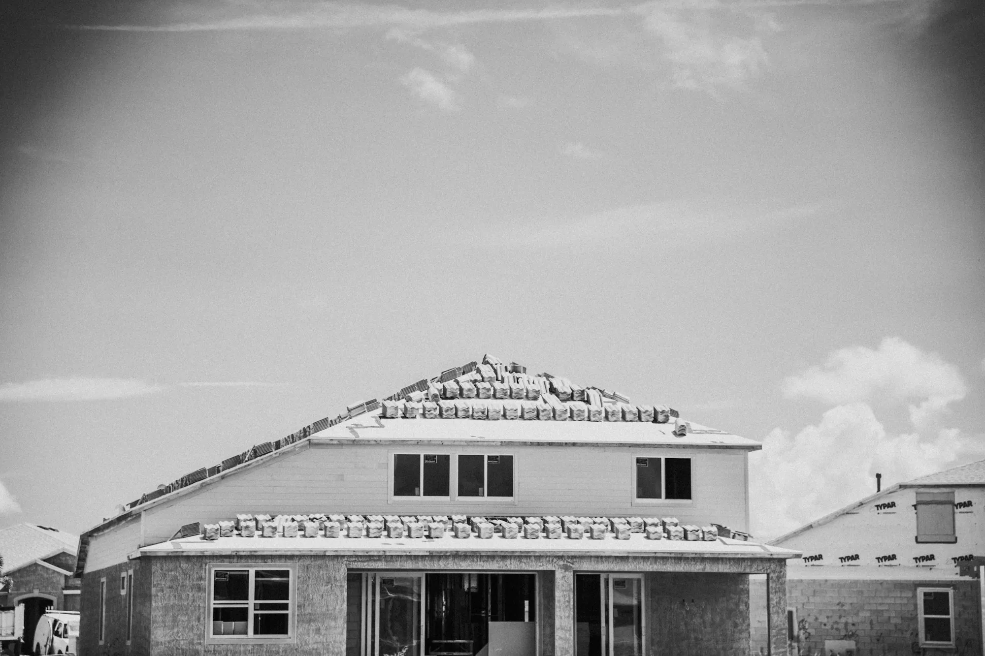 Black and white photo of workers on the roof of a house under construction